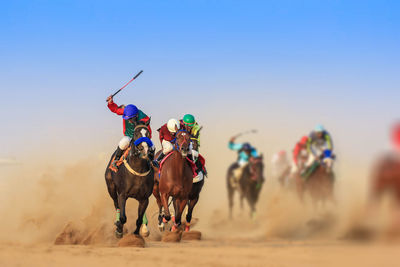 People riding horse on desert against sky