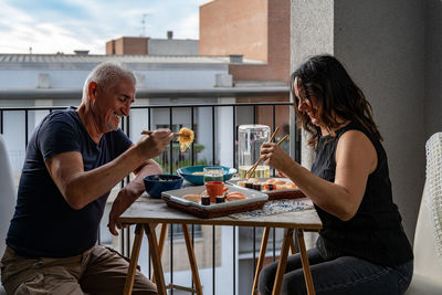 Side view of young woman having food at home