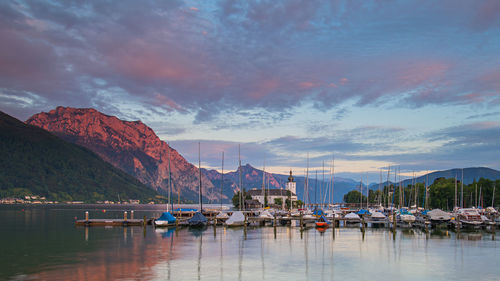 Boats moored in harbor at sunset