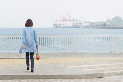 Rear view of woman in city by sea