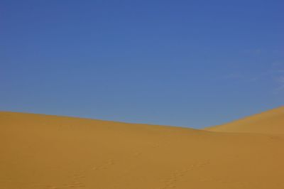 Scenic view of desert against clear blue sky