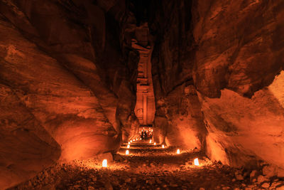 Illuminated walkway amidst rock formations at petra at night