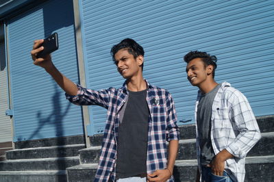 Portrait of smiling friends standing against wall
