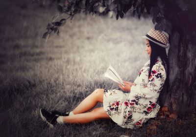 Midsection of woman reading book while sitting on land
