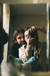 Portrait of young man using mobile phone at home