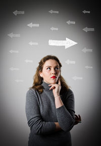 Portrait of a young woman standing against gray background