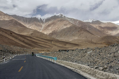 A flat newly built asphalt road calls the foot of the snowy mountain ahead