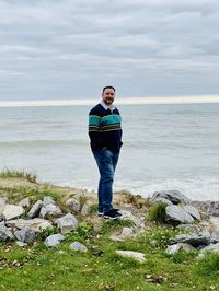 Full length of man on rock in sea against sky