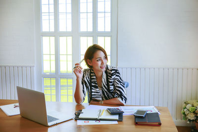 Young woman using phone while sitting on table