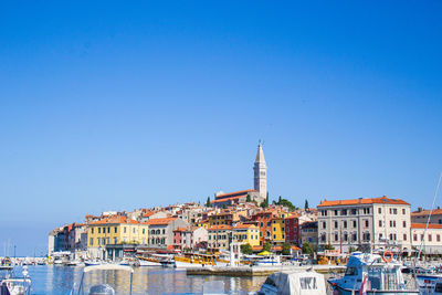 Canal amidst buildings against clear blue sky