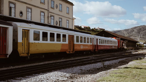 Train on railroad tracks by buildings in city against sky