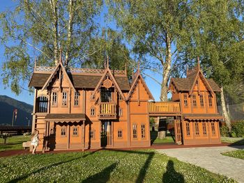 Traditional building by trees on field against sky