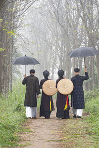 Rear view of people with umbrella on field