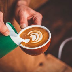 Close-up of hand holding coffee cup on table