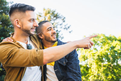 Gay couple standing at park while looking away