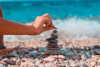 Cropped hand stacking pebbles at beach