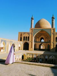 Full length of woman standing against mosque