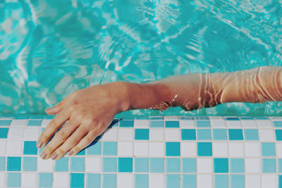 Low section of person lying on swimming pool