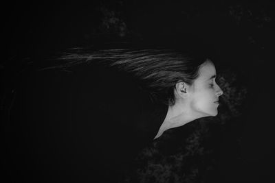 Close-up of young woman against black background