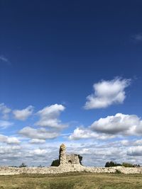 Stone wall on field against blue sky