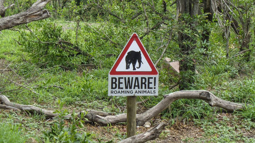 Road sign by trees on field