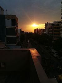 Houses in city against sky during sunset