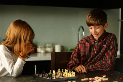 Children playing chess at home kitchen