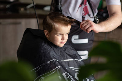Midsection of barber cutting hair of boy