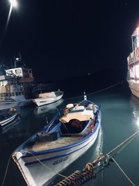 Sailboats moored in harbor against sky in city