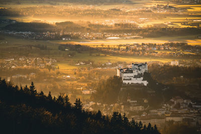 High angle view of trees and buildings against sky at sunset