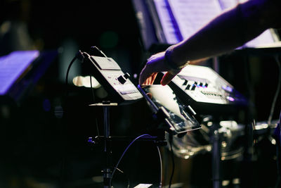 Cropped hand of musician using digital tablet while playing music in nightclub