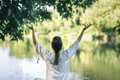 Self-discovery meditation in nature by the lake. woman sitting in lotus position meditating 