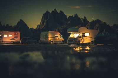 Illuminated building by mountains against sky at night