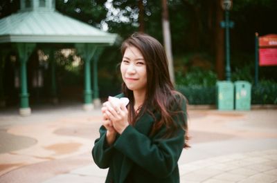 Portrait of smiling beautiful woman holding snack in garden