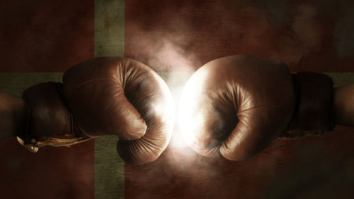 Cropped image of boxers fighting against illuminated danish flag