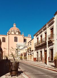 Street amidst buildings against clear blue sky