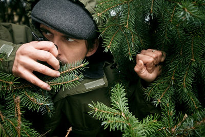 Mid adult man looking away while standing by pine tree