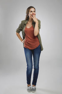 Portrait of young woman standing against white background