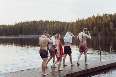 People standing on pier over lake against sky