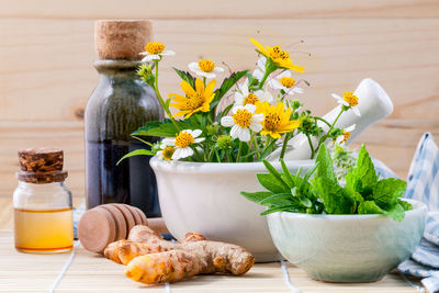 Close-up of flowers in mortar and pestle by bottle on table