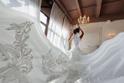 Full length of woman standing on white bed