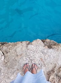 Low section of woman standing against sea