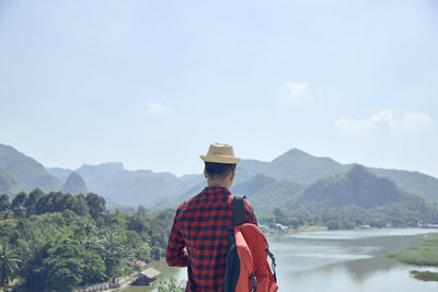 Rear view of man looking at mountains against sky