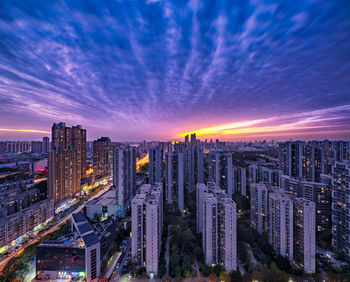 Modern buildings in city against sky during sunset