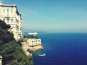 Buildings by sea against blue sky