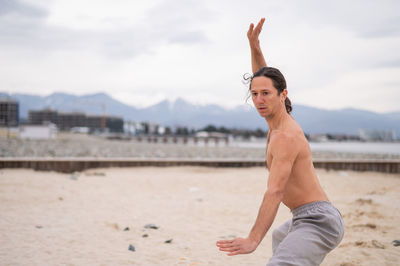 Full length of young woman exercising at beach