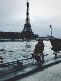 Man on boat in city against cloudy sky