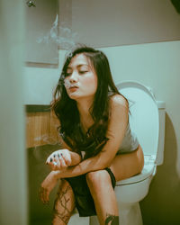 Young woman looking away while sitting in kitchen