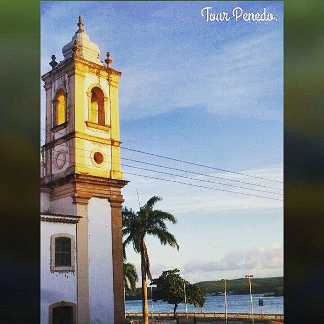 building exterior, architecture, built structure, sky, tree, palm tree, low angle view, cloud - sky, guidance, tower, outdoors, cloud, sunset, no people, water, nature, clock tower, sea, day, communication