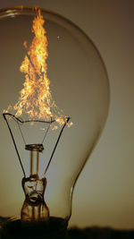 Close-up of illuminated light bulb against sky